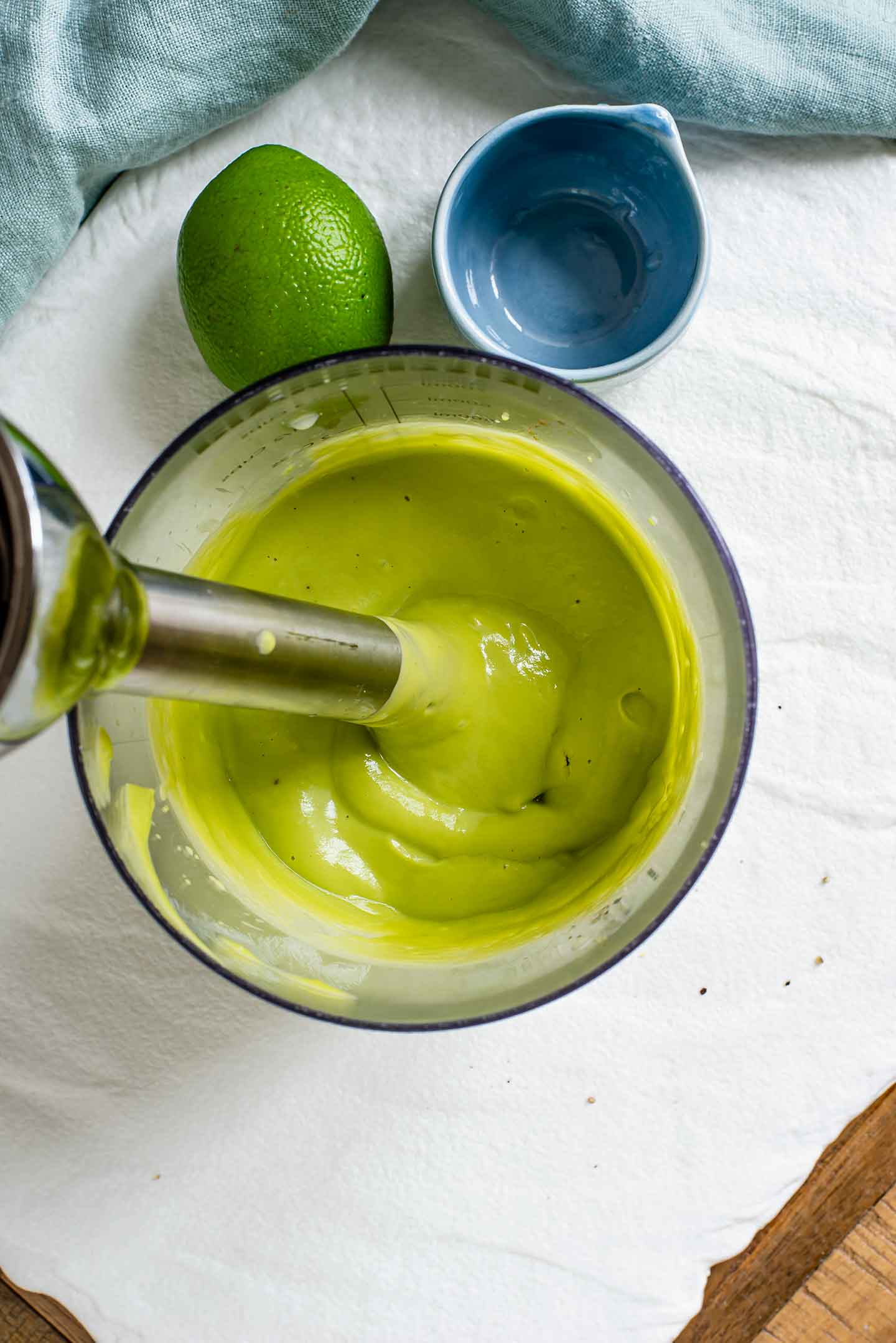 Top down view of an immersion blender submerged in a thick and creamy avocado lime dressing.