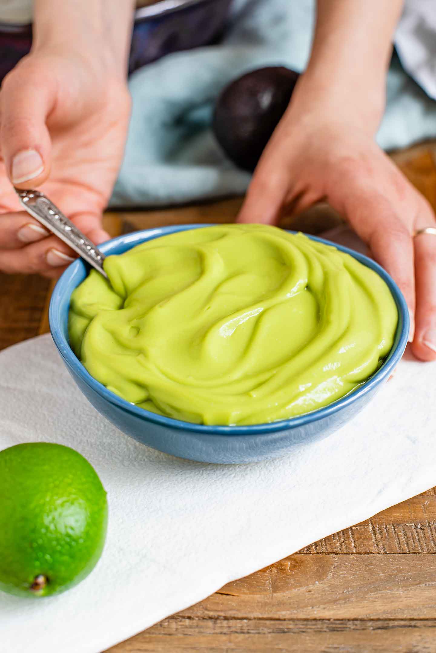 Side view of a thick and creamy avocado lime dressing swirled in a small dish. 