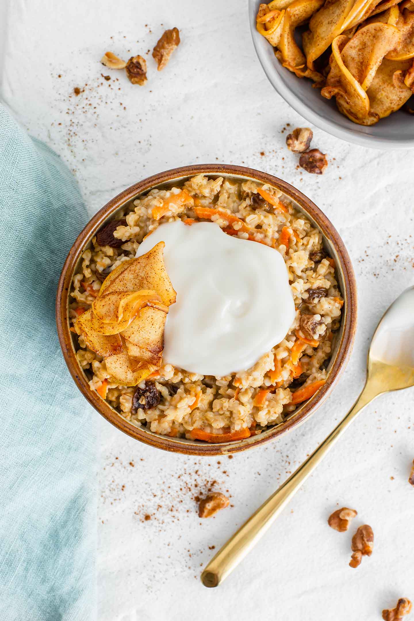 Top down view of carrot cake oatmeal in a bowl topped with coconut yogurt and warm cinnamon apples.