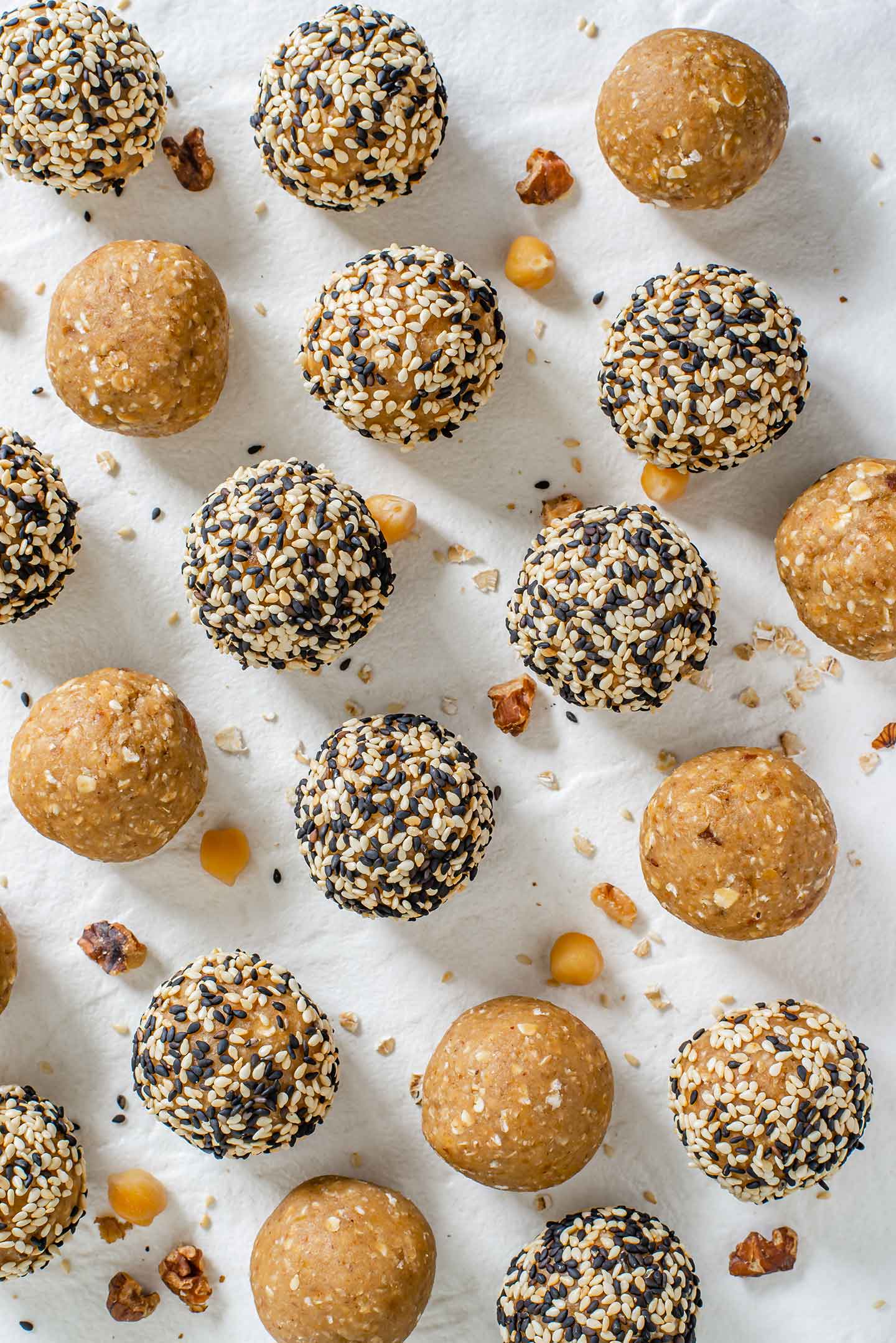 Top down view of chickpea tahini protein balls on a white tray. Some balls are rolled in toasted sesame seeds.