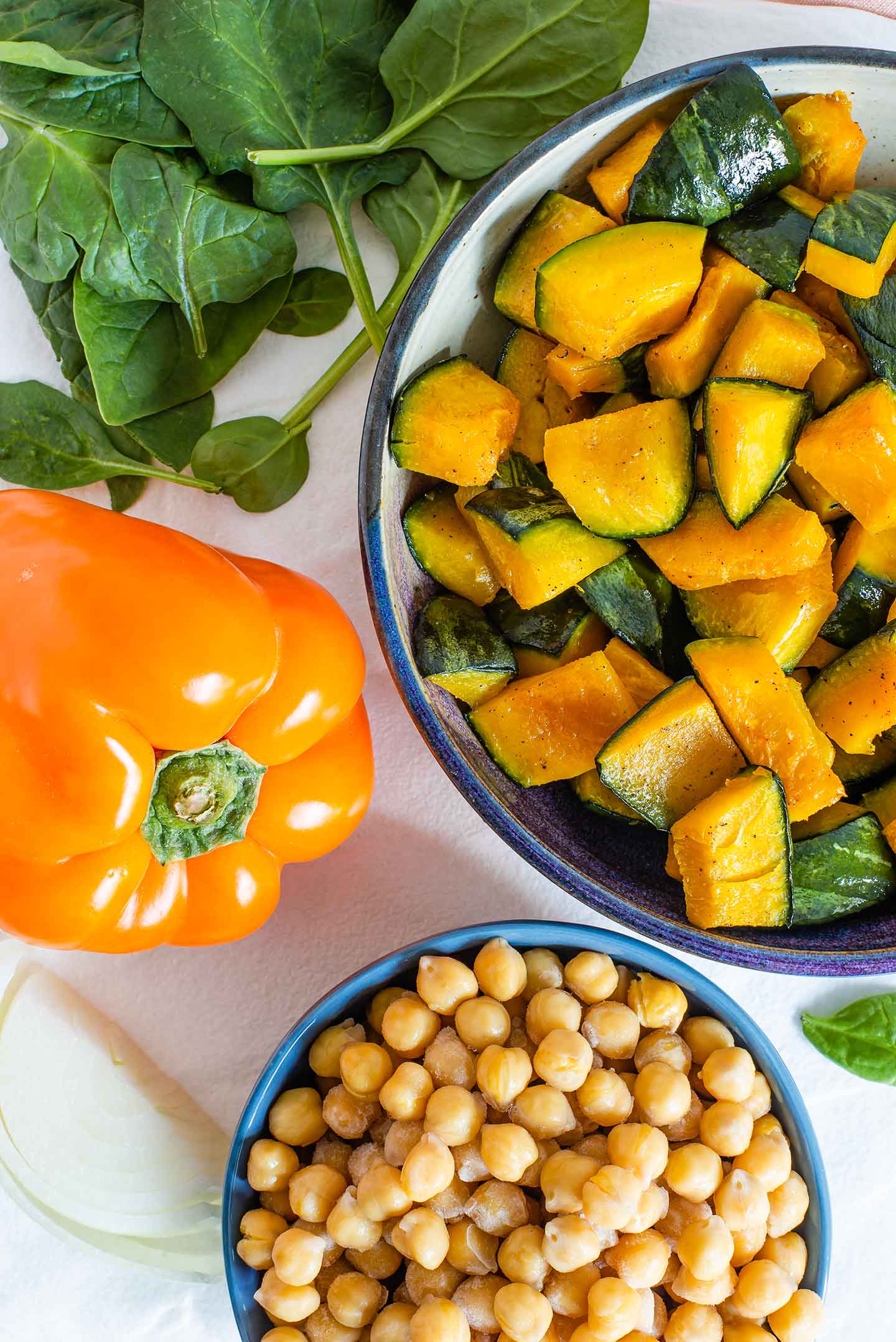 Top down view of cubed and roasted kabocha squash with onion, chickpeas, bell pepper, and spinach.