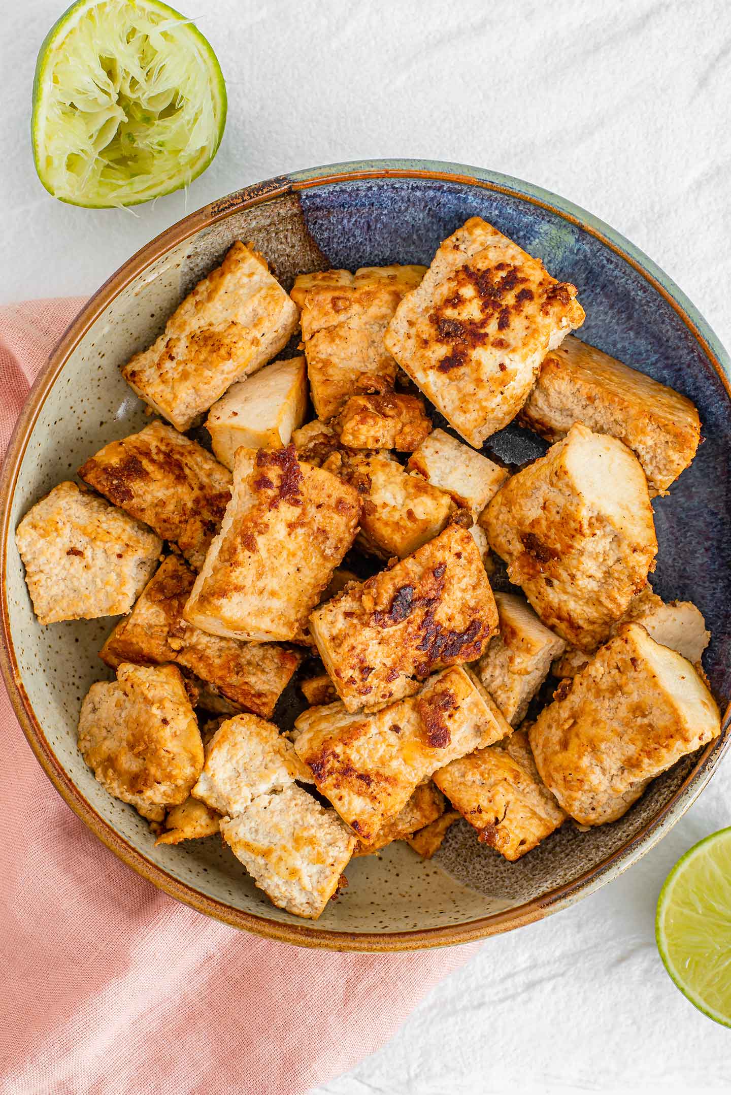 Top down view of golden brown chunks of lime tofu in a bowl.