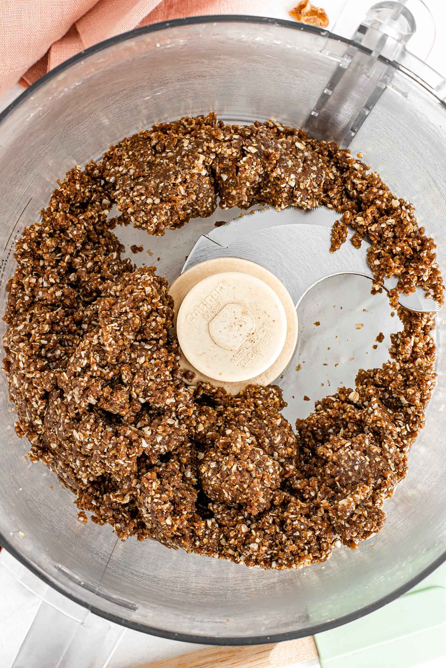 Top down view of a sticky somewhat crumbly dough in the bowl of a food processor.