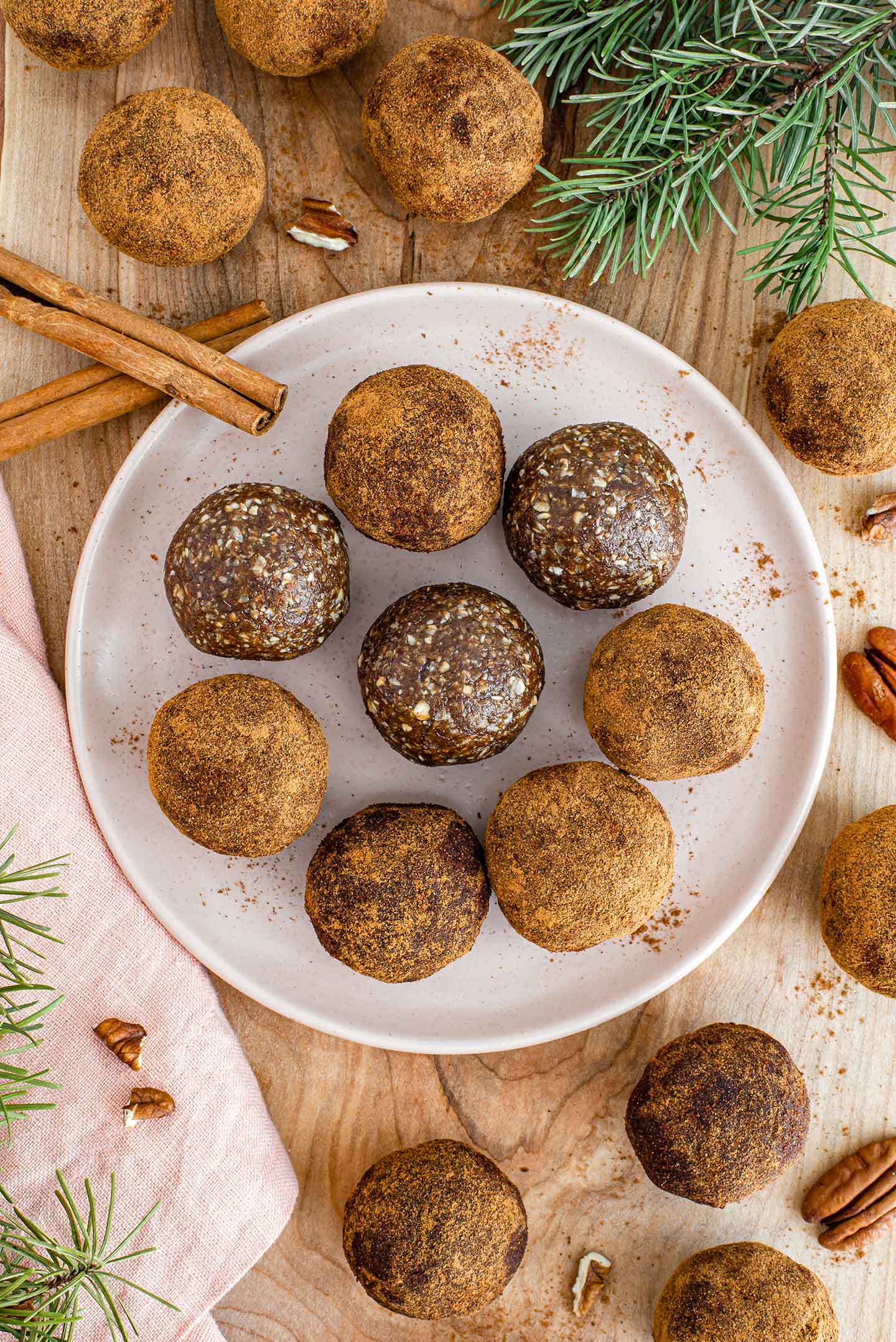 Top down view of gingerbread energy balls on a plate and wooden tray. Some are dusted in cinnamon. 