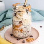 A mason jar filled with peanut butter chia oats, banana slices and chocolate chips.