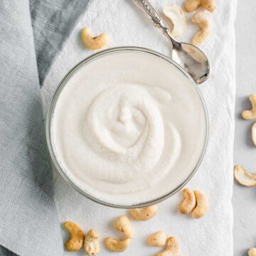 Top down view of dairy-free sour cream in a small glass dish with cashews surrounding.