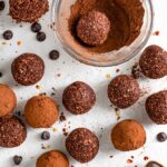 Top down view of chocolate chilli energy balls being rolled in spicy cocoa powder.