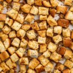 Top down view of a baking sheet filled with crispy homemade croutons.