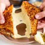 Close up of cashew mozzarella stretching between two halves of a grilled cheese sandwich.