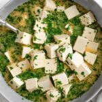 Top down view easy tofu feta cubes in a bowl with marinade and chopped parsley.