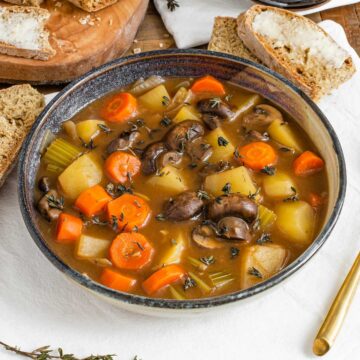 Side view of a bowl of vegan Irish stew filled with mushrooms, carrots and potatoes.