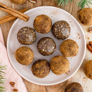 Top down view of gingerbread energy balls on a plate. Some are rolled in cinnamon.