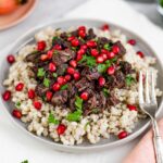 Jackfruit fesenjan on a bed of barley is topped with pomegranate arils and fresh parsley.