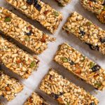 Top down view of puffed rice granola bars with toasted almonds, seeds, and dried fruit.