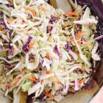 Top down view of creamy and colourful vegan coleslaw in a ceramic salad bowl.