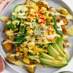 Top down view of breakfast potatoes under tofu scramble and loaded with toppings.