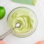 Top down view of light green avocado lime crema swirled in a small glass dish.