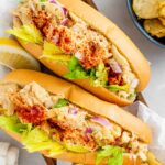 Top down view of two fish-less lobster rolls bursting with hearts of palm and garnished with celery leaves.