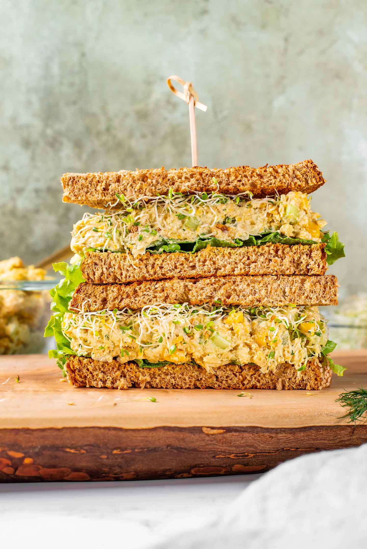 Side view of a sliced chickpea smash sandwich with charred corn. The sandwich halves are stacked on top of one another and filled with the creamy mixture.