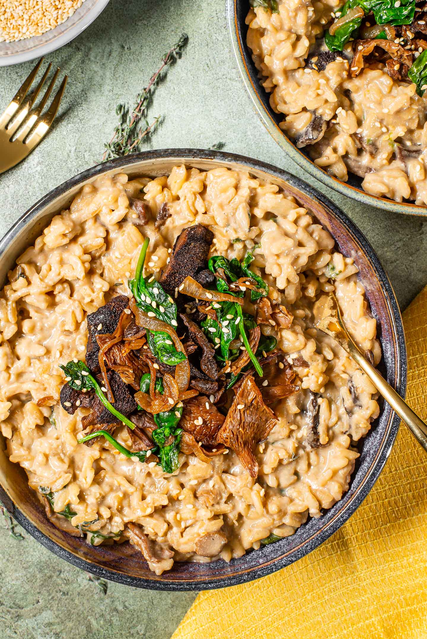 Top down view of two dishes of vegan mushroom risotto. The texture is creamy and the mushroom topping is a beautiful garnish.