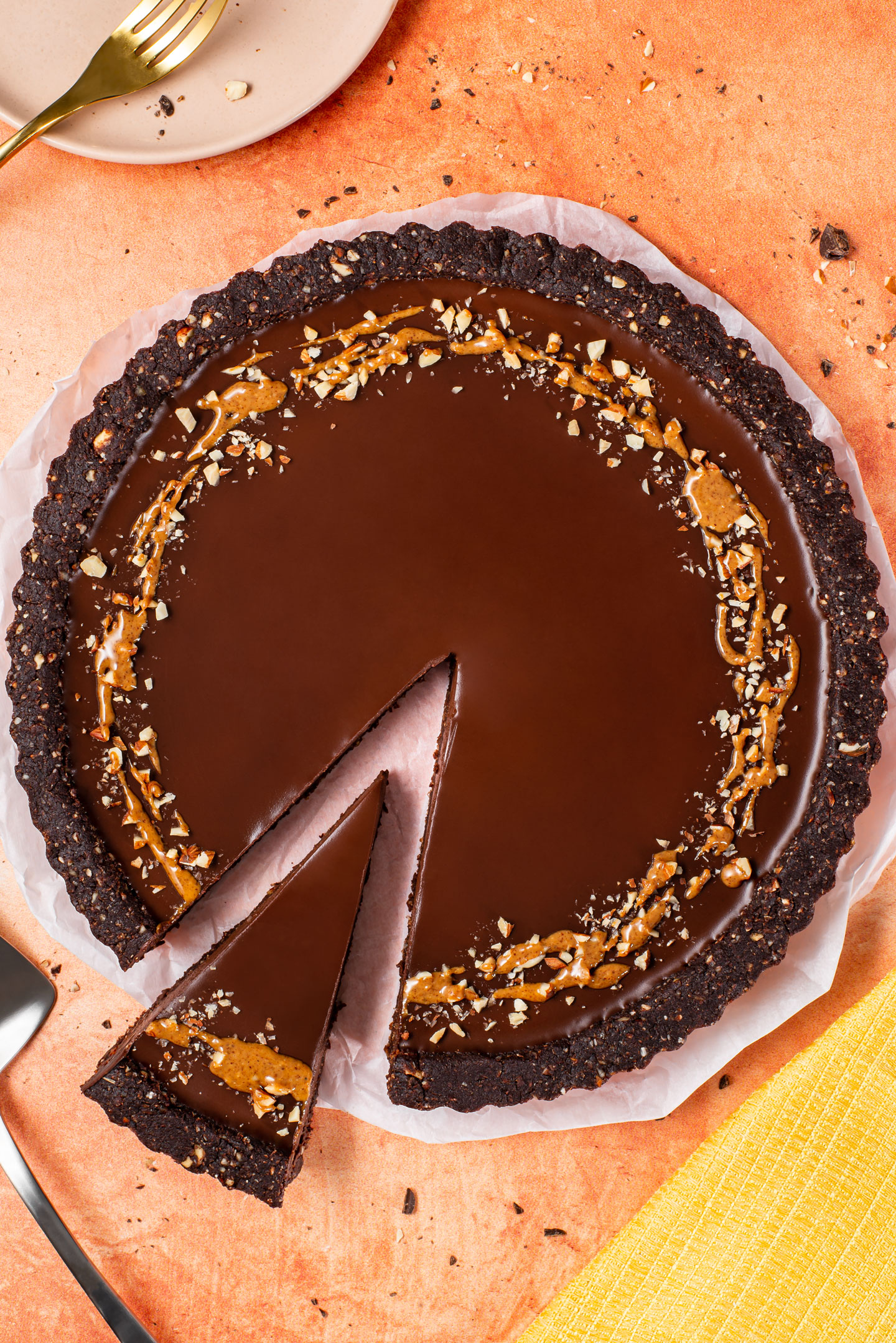A rich vegan chocolate almond tart with a smooth chocolate filling and one slice pulled away.