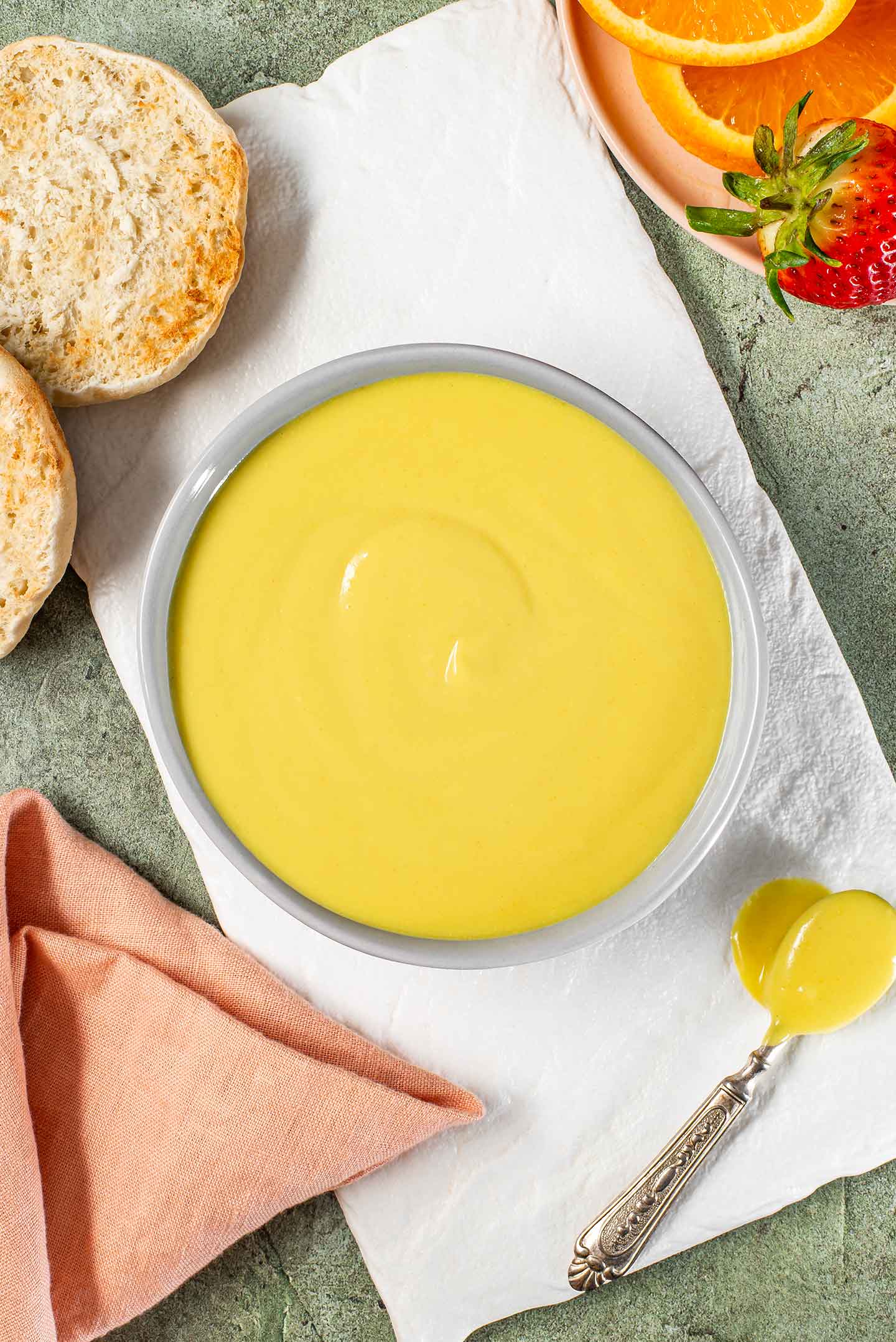Top down view of vegan hollandaise sauce in a small bowl. The sauce is yellow in colour and thick but pourable.