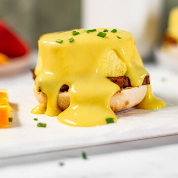 A thick vegan hollandaise sauce drips down the sides of a vegan eggs benedict.