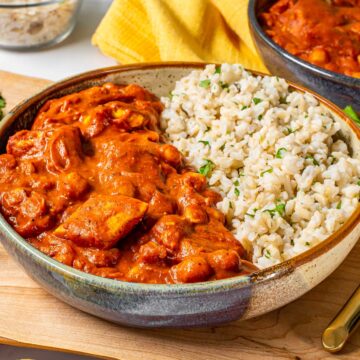 Tofu and chickpeas covered in a thick reddish orange gravy make up a vegan butter chicken served with brown rice.