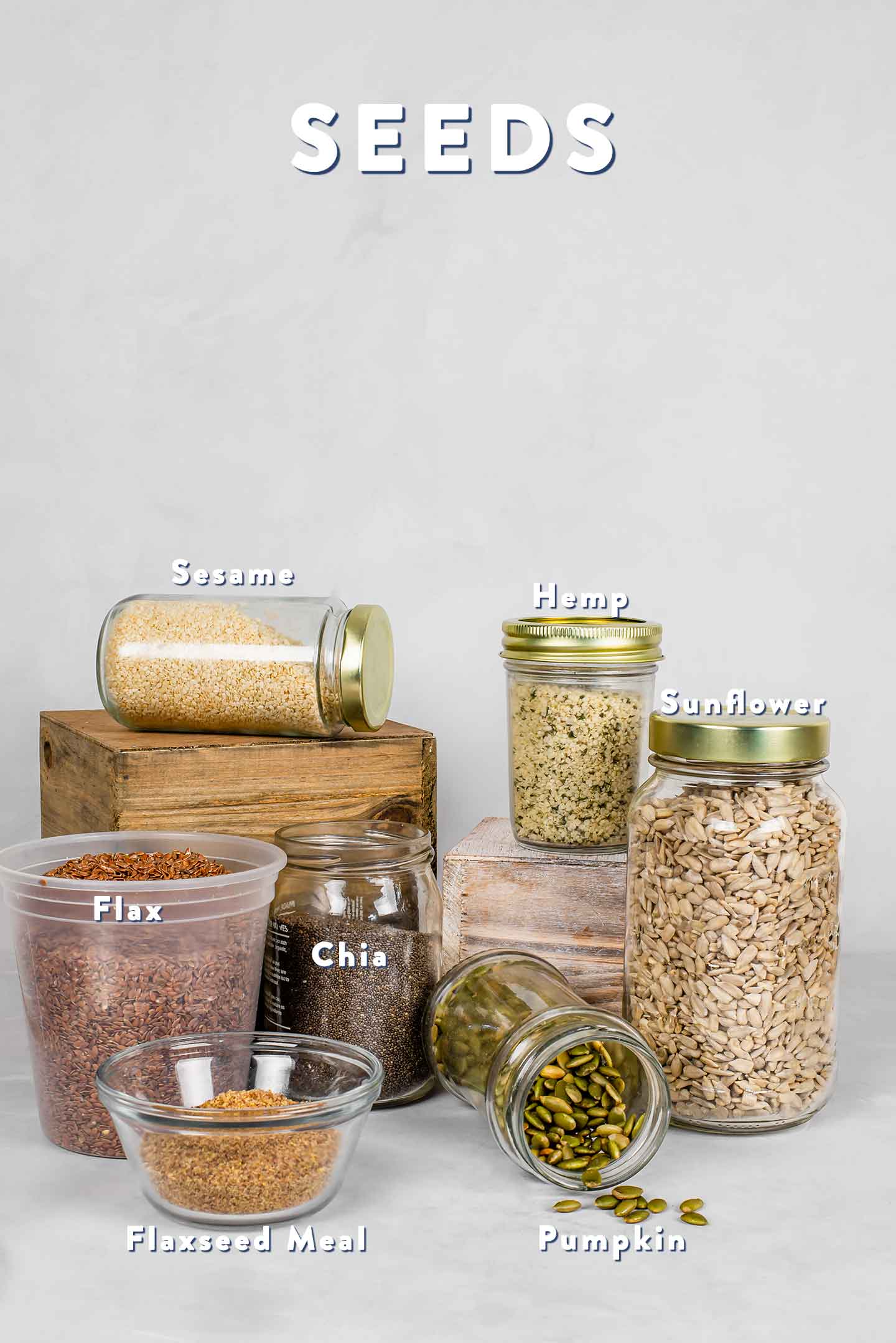 A grouping of different seed varieties in glass jars. Both whole flaxseed and ground flaxseed meal are pictured.