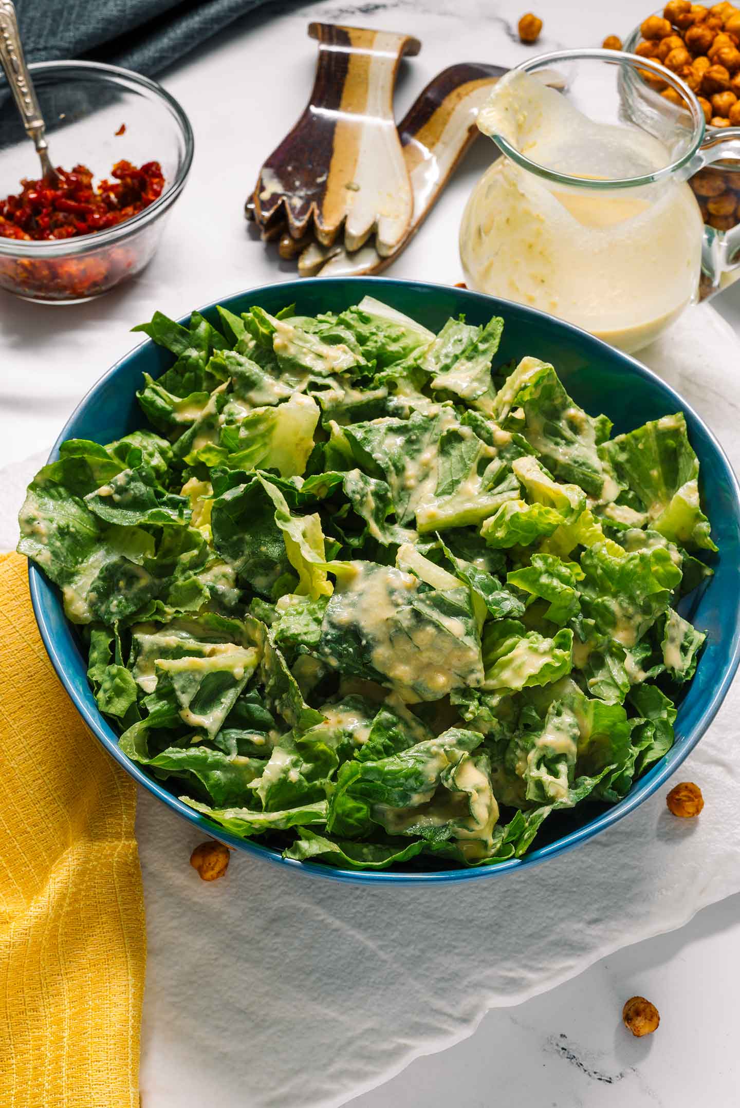 Top down view of romaine lettuce dressed with a creamy dairy-free caesar dressing. Leftover dressing fills a jar nearby.
