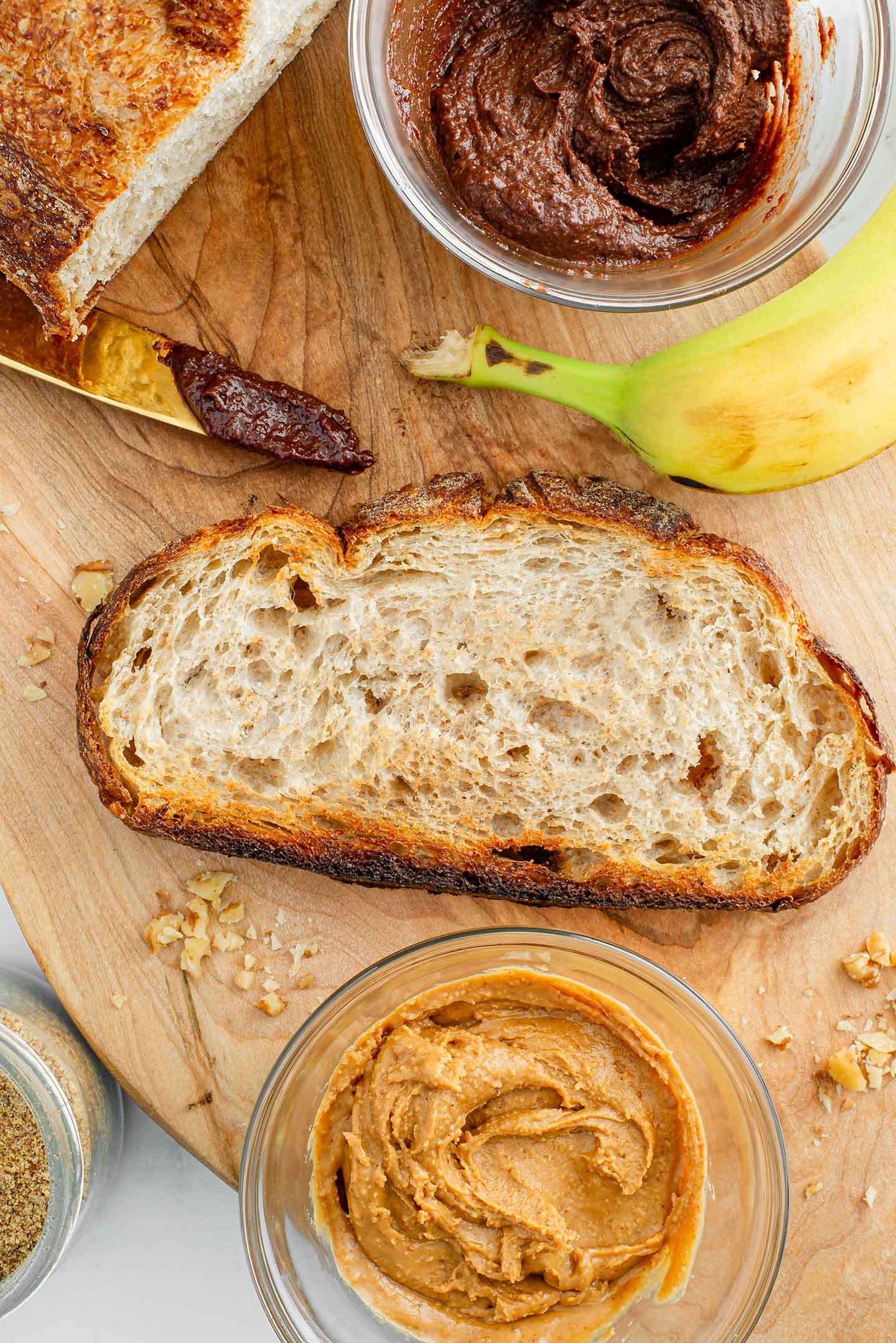 Top down view of a toasted slice of sourdough bread and the sandwich ingredients on a wooden tray.