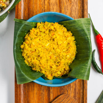 Top down view of Basa Bali spice paste in a small bowl lined with banana leaf. The paste is golden and textured with the herbs and spices it is comprised of.