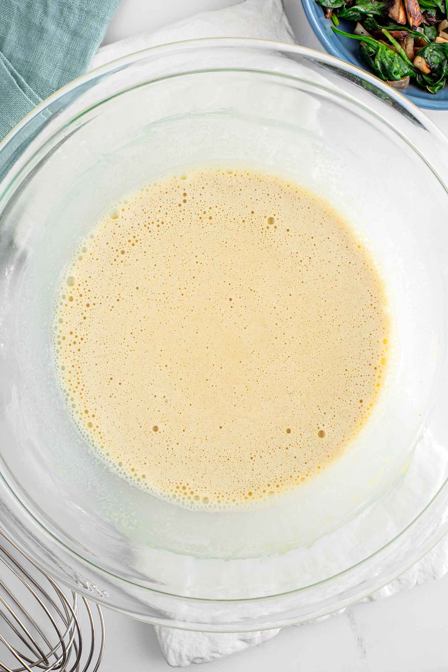 Top down view of a vegan omelette batter in a glass bowl. The batter has a thick but pourable consistency and is lump free. 