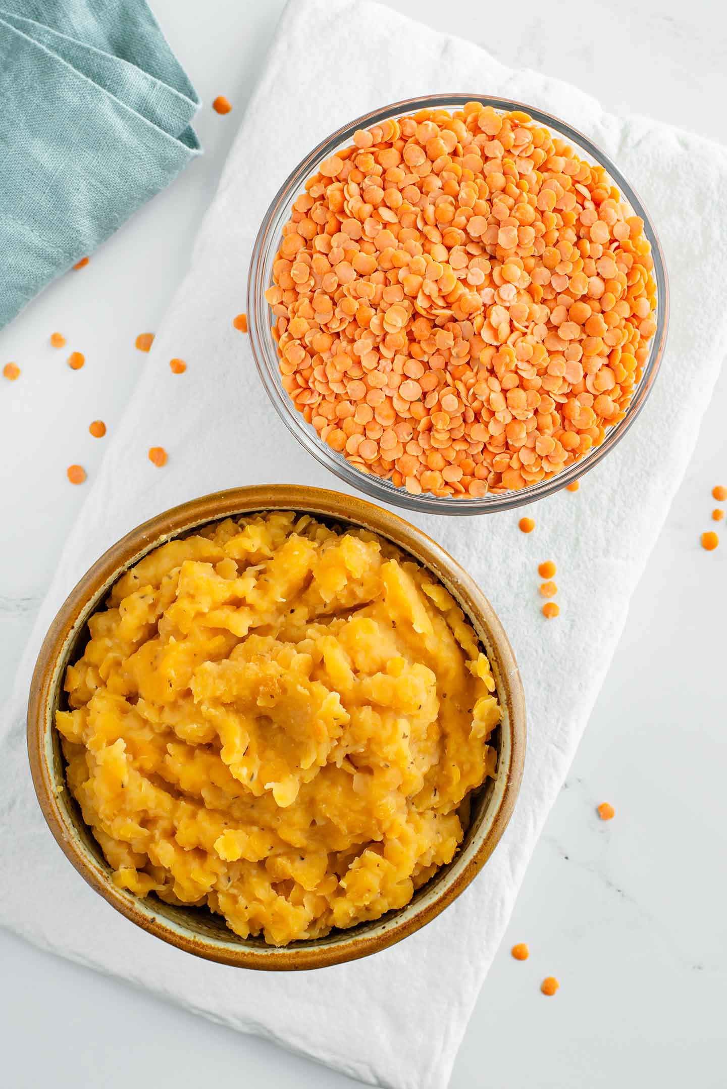 Top down view of two small bowls. One is filled with raw split red lentils and the other is filled with cooked split red lentils.