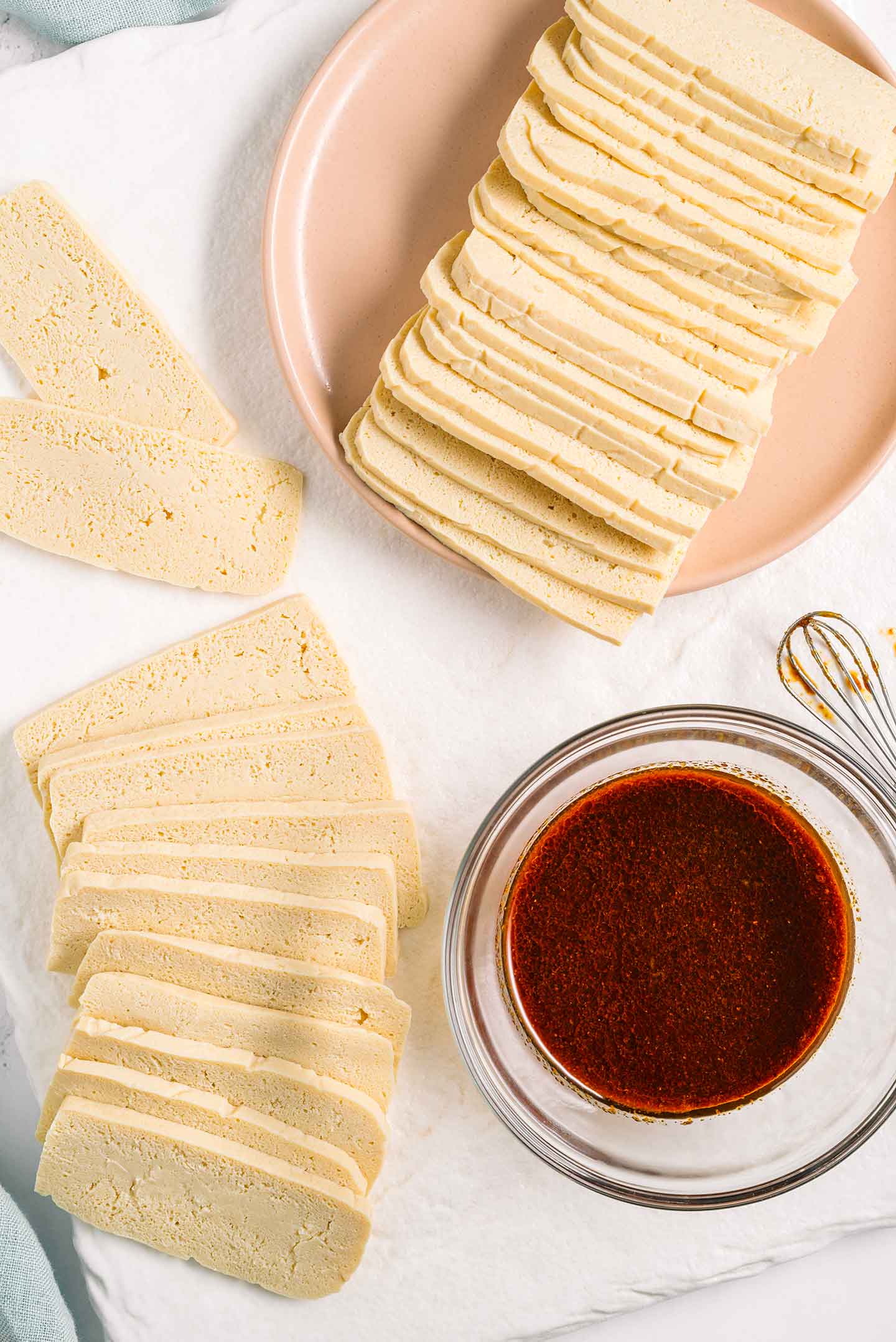 Top down view of thinly sliced previously frozen tofu and a mixed marinade in a small bowl.