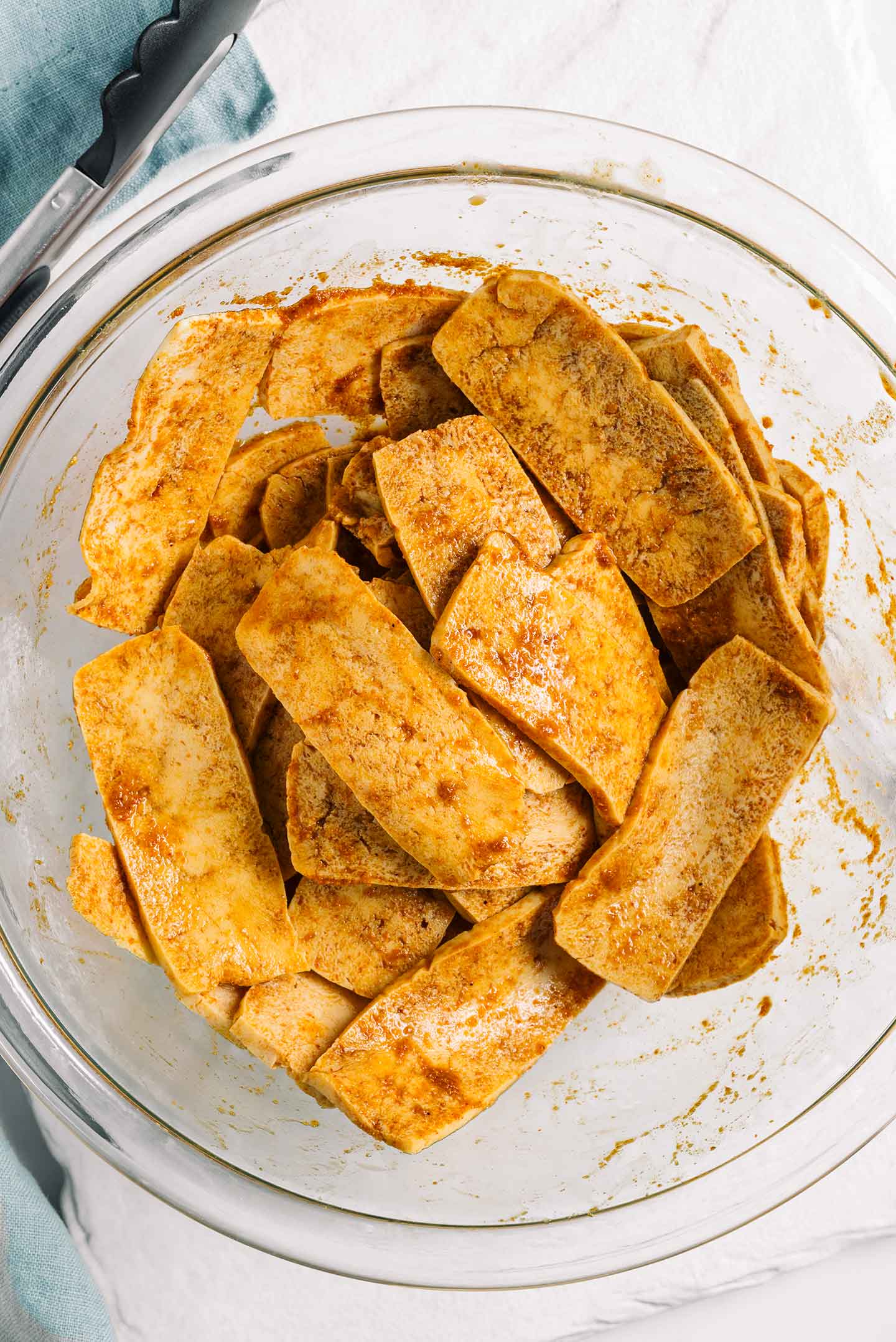 Top down view of tofu shaved meat resting in a marinade. 