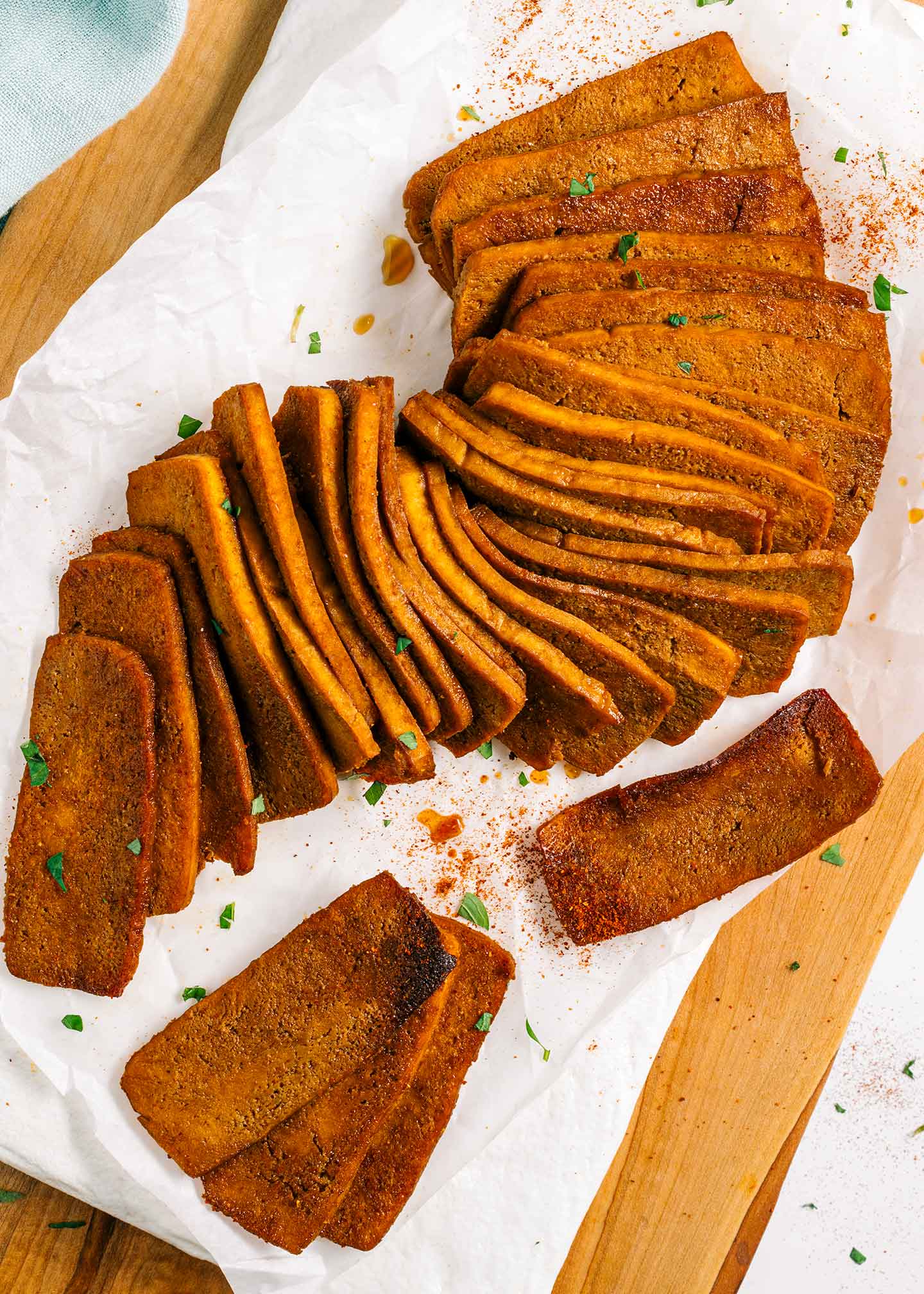 Top down view of tofu shaved meat displayed on a white tray. the tofu slices are pliable and bend like an accordion on the tray. They are golden and crispy but still look juicy.