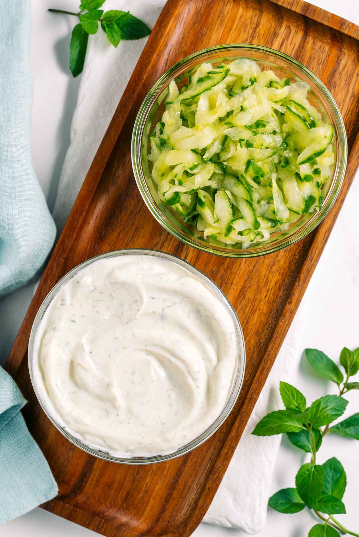 Top down view of grated and strained cucumber in a small bowl. Next to it is a bowl of a creamy tofu spread.