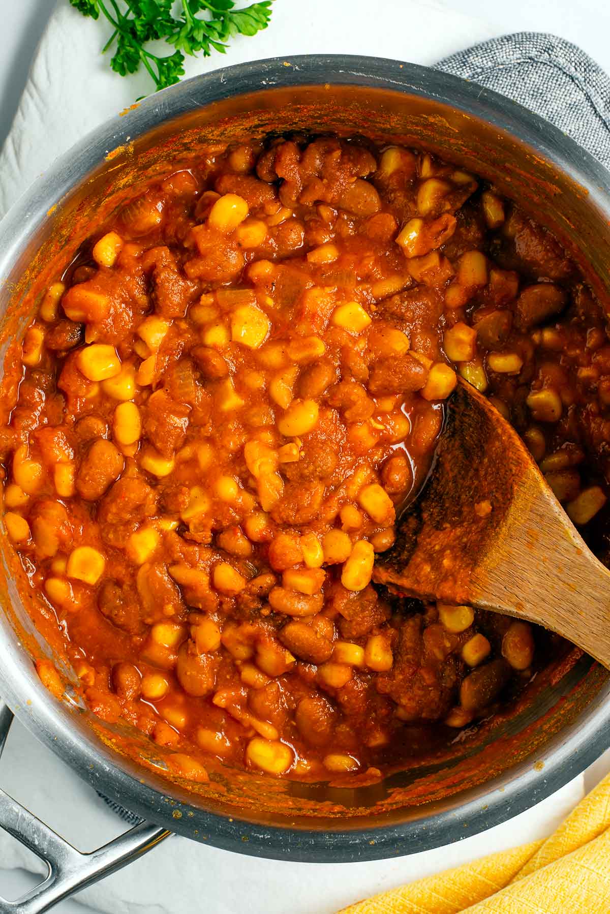 Top down view of cooked githeri in a pot. The tomato based gravy is thicker than some variations of githeri.