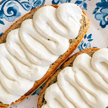 Top down view of fluffy whipped tofu piped in waves onto a slice of toasted bread. The tofu is creamy and pillowy.