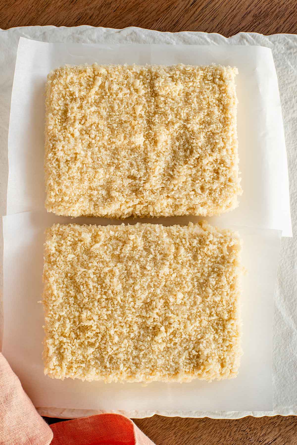 Top down view of two slices of tofu coated in panko breadcrumbs before being fried or air fried.